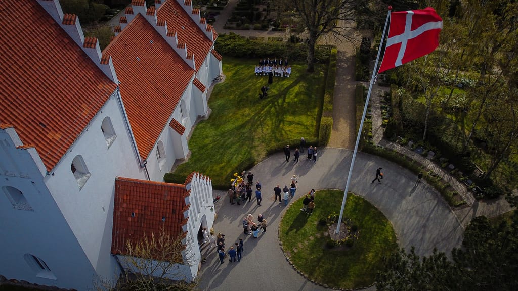 dronefoto af konfirmationsgæster foran kirken